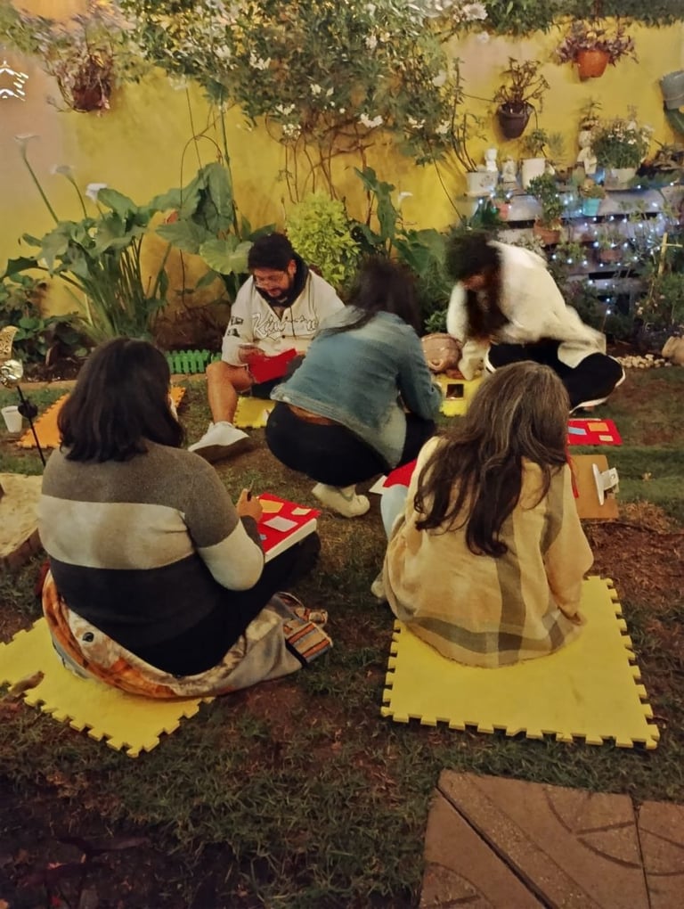 Group of children sitting on yellow mats in a bright garden space with hanging plants
